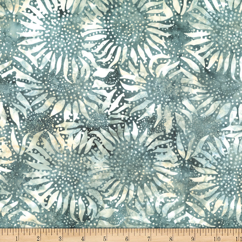 Fabric with a sunflower pattern in teal and beige on a 1/4 inch ruler for scale.